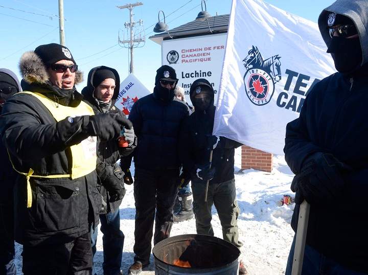 Canadian Pacific Railway workers huddle around a fire while on strike at the Cote Saint-Luc railyard in Montreal on Monday, Feb. 16, 2015.