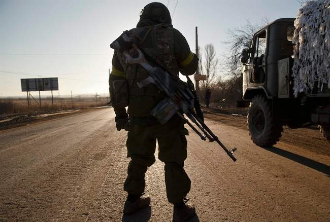 A Ukrainian serviceman stands on the road outside Artemivsk, Ukraine, after pulling out of Debaltseve, Wednesday, Feb. 18, 2015.