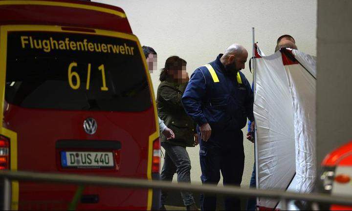 An airport employee accompanies people towards a protected area reserved for relatives of the Germanwings plane crash victims on March 24, 2015 at the airport in Duesseldorf, western Germany,
