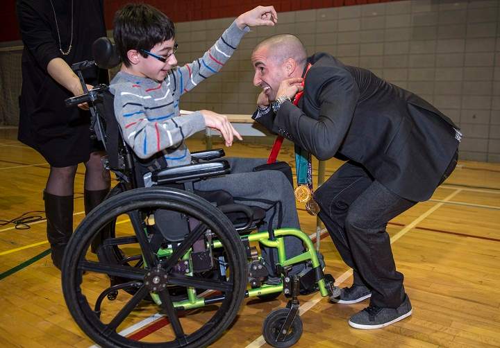 Canadian Paralympic swimmer Benoit Huot receives one of his five replacement medals from Vincent, 13, during a ceremony Monday, March 9, 2015 in Montreal.