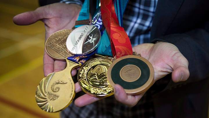 Canadian Paralympic swimmer Benoit Huot holds up his five replacement medals during a ceremony Monday, March 9, 2015 in Montreal.