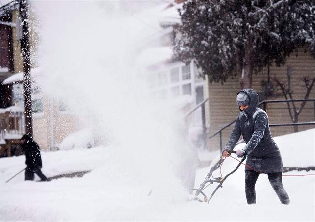 People clear snow from their sidewalks and streets after a large amount of snow fell in Toronto on Monday, February 2, 2015.