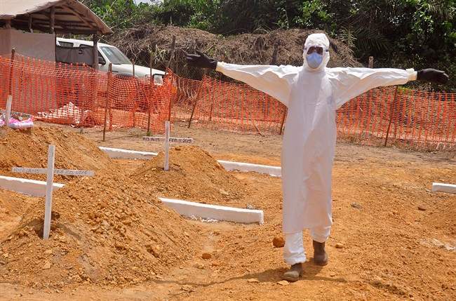 In this photo taken on Wednesday, March 11, 2015, a health worker holds up his arms after he and others buried a person that they suspect died form the Ebola virus at a new graveyard on the outskirts of Monrovia, Liberia.