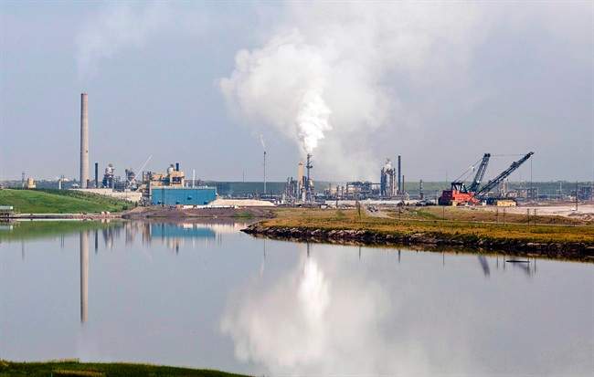 An oil sands facility is reflected in a tailings pond near Fort McMurray, Alta., on July 10, 2012. 