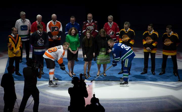Vancouver Canucks’ Henrik Sedin (33) and Philadelphia Flyers’ Claude Giroux (28) face off for a ceremonial puck drop with members of Pat Quinn’s family during a ceremony to honour Quinn prior to the first period of NHL action in Vancouver, B.C. Tuesday, March. 17, 2015.