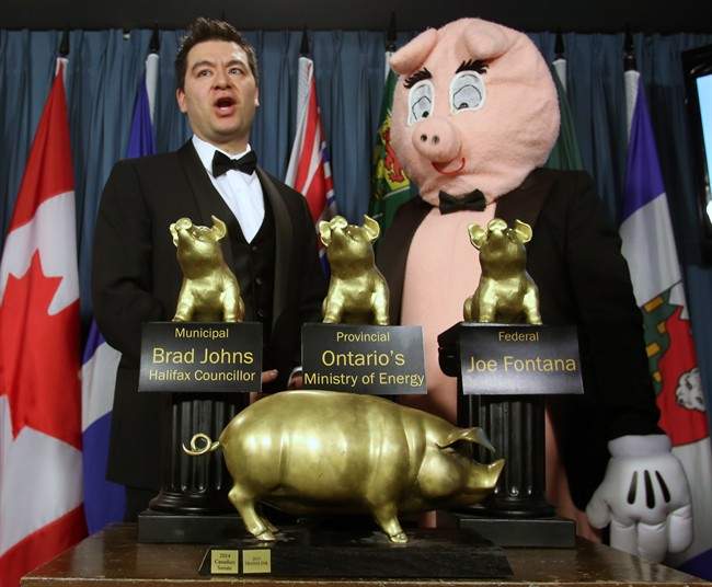 Canadian Taxpayers Federation Director Aaron Wudrick and pig mascot Porky the Waste Hater stand behind the CTF awards after they presented the 17th Annual Teddy Government Waste Award Winners during a news conference in Ottawa, Wednesday, March 4, 2015.