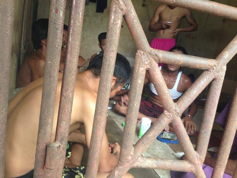 In this Saturday, Nov. 22, 2014 photo, Thai and Burmese fishing boat workers sit inside a cell at the compound of a fishing company in Benjina, Indonesia.