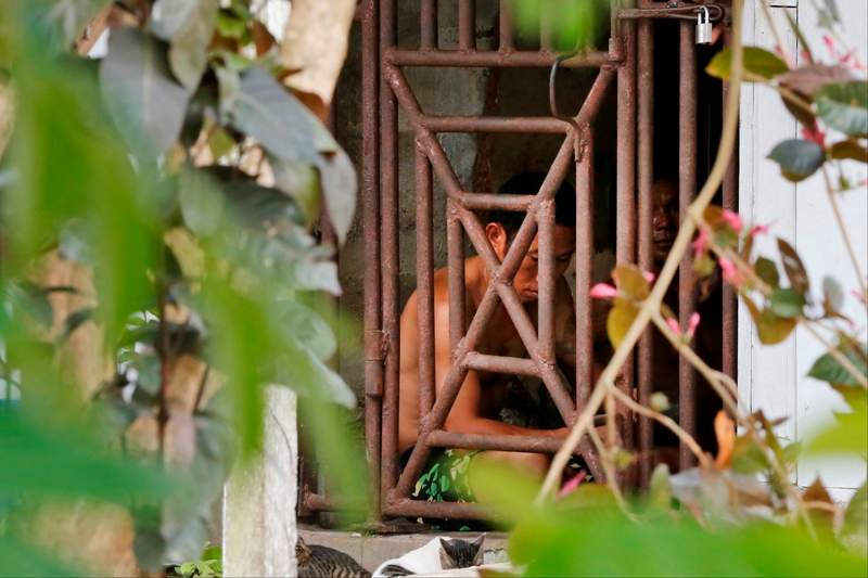 In this Saturday, Nov. 22, 2014 photo, Thai and Burmese fishing boat workers sit behind bars inside a cell at the compound of a fishing company in Benjina, Indonesia.