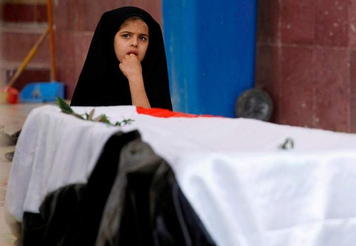 Mariam Ali, 5, sits next to the flag-draped coffin of her brother Ahmed Ali, 6, who was killed in a car bomb attack in Najaf, south of Baghdad, Iraq, in Mar. 2014. The U.N. says at least 1,100 Iraqis were killed in February, including more than 600 civilians.