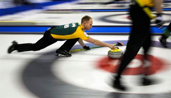 Northern Ontario skip Brad Jacobs, left, launches a rock as his team plays New Brunswick during curling action at the Brier.