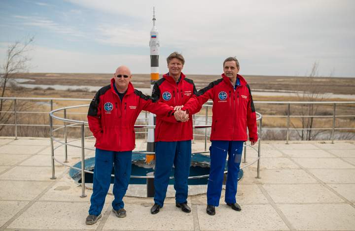 Expedition 43 NASA Astronaut Scott Kelly, left, Russian Cosmonauts Gennady Padalka, center, and Mikhail Kornienko of the Russian Federal Space Agency (Roscosmos) pose for a group photo near a model of the Soyuz rocket during media day, Saturday, March 21, 2015 at the Cosmonaut Hotel in Baikonur, Kazakhstan.