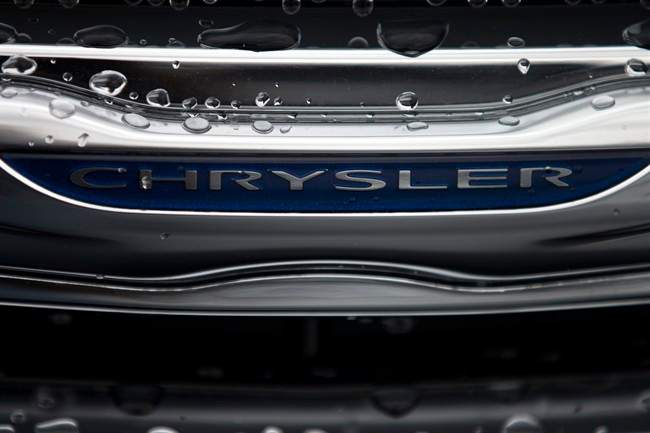 In this Dec. 2, 2014 photo, a Chrysler minivan sits under rain at a car lot in San Diego. Major automakers report vehicle sales for February on Tuesday, March 3, 2015. (AP Photo/Gregory Bull)