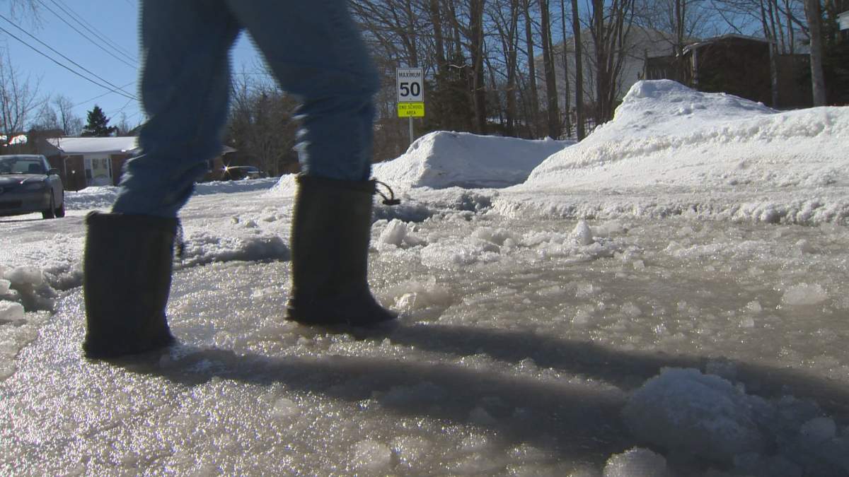 Global News Camera Operator Paul DeWitt walks through a two-metre puddle, formed by thick ice pack on Autumn Place, in Cole Harbour.