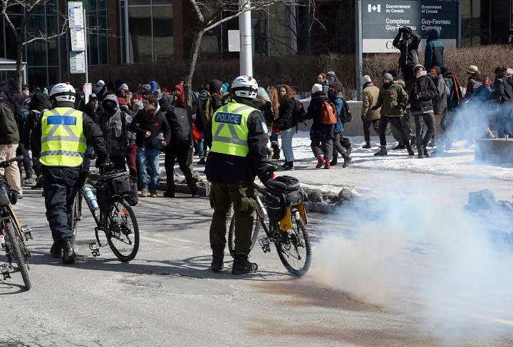 A smoke bomb lands by police during a demonstration by students on the first day of a student strike Monday, March 23, 2015 in Montreal.