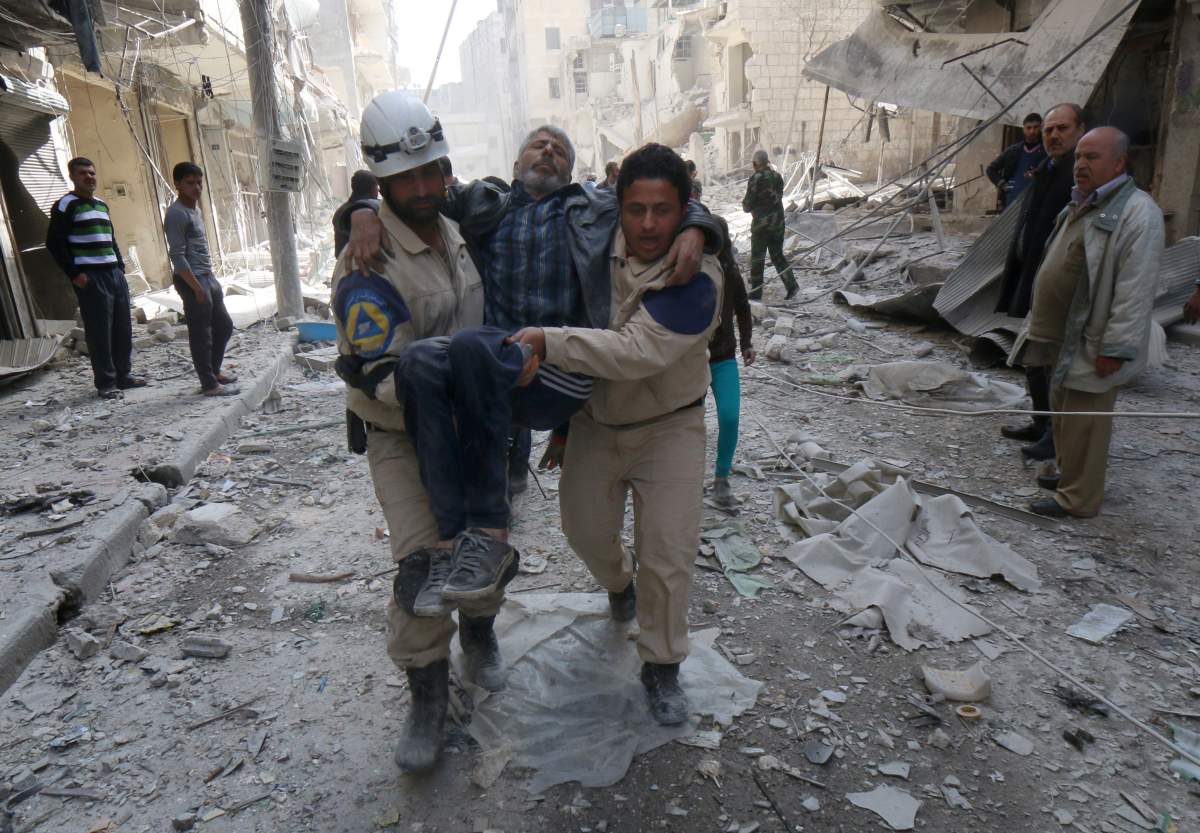 Emergency personnel carry an injured man following air strikes by government forces helicopters on the eastern Shaar neighbourhood of the northern Syrian city of Aleppo on March 27, 2015.