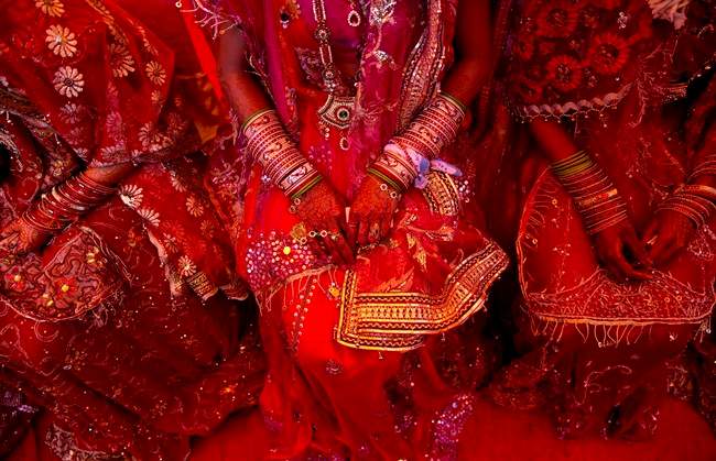 FILE - In this Feb. 20, 2015 file photo, Indian brides from impoverished families, dressed in wedding finery, wait for their grooms to arrive during a mass marriage ceremony in New Delhi, India.