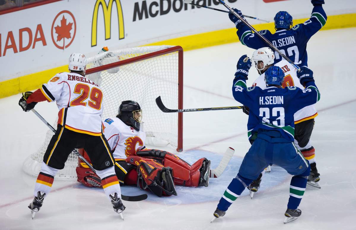 Vancouver Canucks' Daniel Sedin and Henrik Sedin celebrate Daniel's goal against Calgary Flames' goalie Jonas Hiller. 