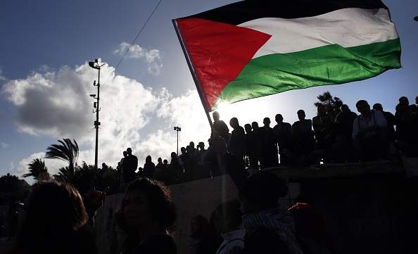 Palestinians wave a giant national flag during a demonstration marking Land Day on March 30, 2015 near the Damascus Gate in Jerusalem's Old City. 