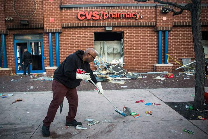 Jerald Miller helps clean up debris from a CVS pharmacy that was set on fire yesterday during rioting after the funeral of Freddie Gray, on April 28, 2015 in Baltimore,