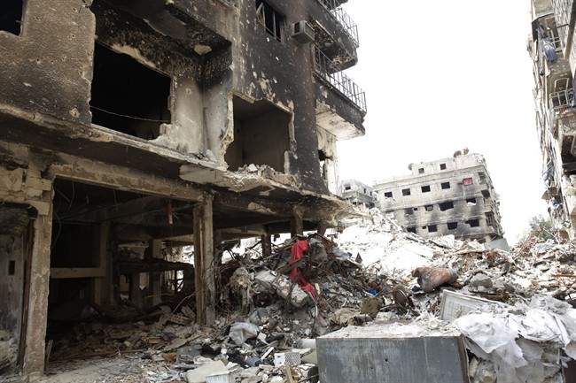 Rubble and heavy damage remain on a deserted street during a government escorted visit to Yarmouk refugee camp in Damascus, Syria, Thursday, April 9, 2015.