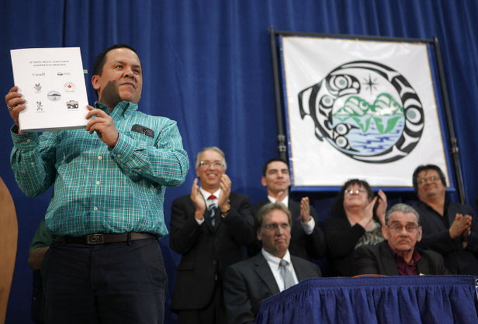 Songhees First Nation Chief Ron Sams holds up signed documents with Five Te'mexw member First Nations Canada and British Columbia, towards an agreement-in-principle for final treaties on Vancouver Island for approximately 1,565 hectares of crown land during an announcement at the Songhees Wellness Centre in Victoria, B.C., Thursday April 9, 2015. THE CANADIAN PRESS/Chad Hipolito.