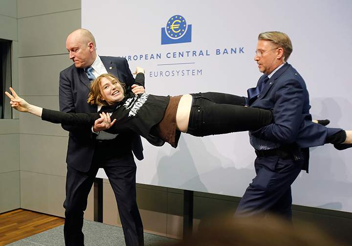 A Femen activist is carried away after attacking ECB President Mario Draghi during a press conference of the European Central Bank, ECB, in Frankfurt, Germany, Wednesday, April 15, 2015.