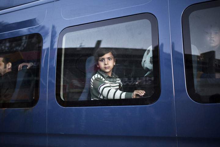 A young migrant looks through a police bus window in the port of Lesvos island on April 17, 2015.