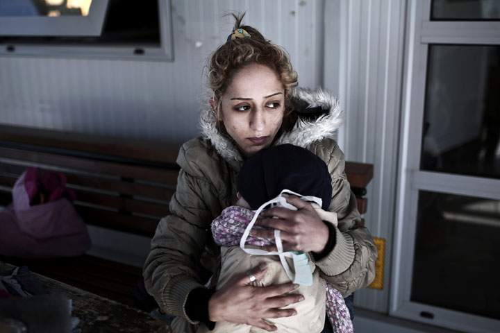 A shipwrecked migrant holds her child after disembarking from a rescue vessel in the port of Lesvos island on April 17, 2015.