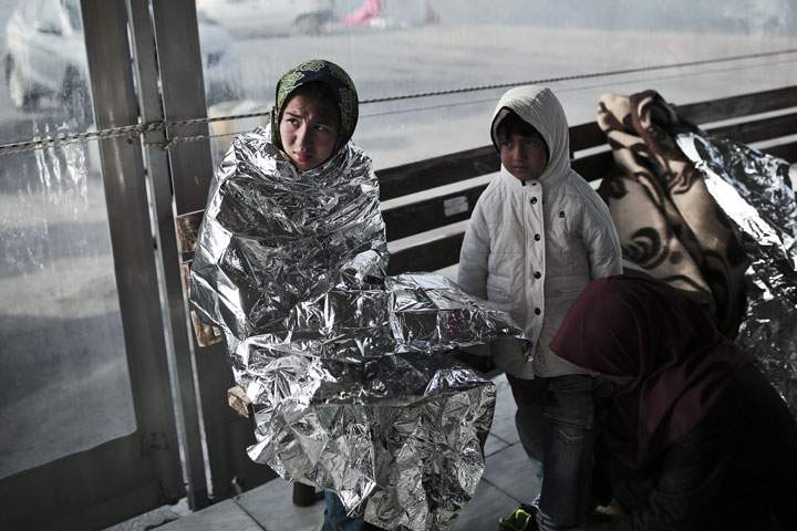 Immigrants gather in front of Hellenic coast guard as they arrive in the port on the island of Lesbos on April 18, 2015.
