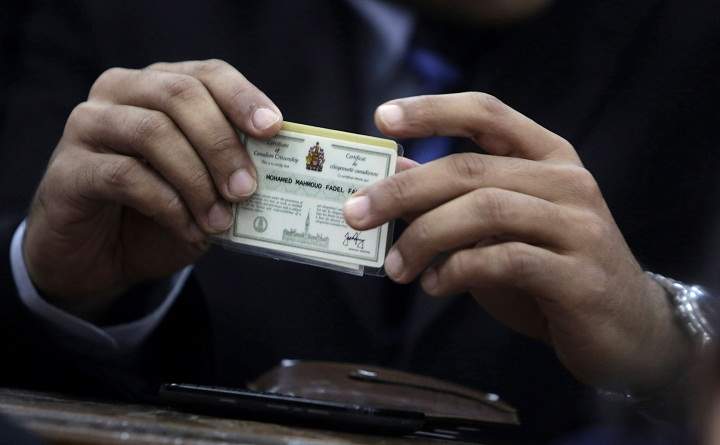 Canadian Al-Jazeera English journalist Mohamed Fahmy, holds his Canadian citizenship card as he attends his retrial at a court in Cairo, Egypt, Monday, Feb. 23, 2015.