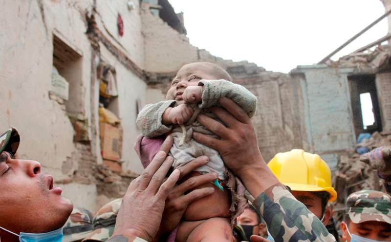 In this Sunday, April 26, 2015, photo taken by Amul Thapa and provided by KathmanduToday.com, four-month-old baby boy Sonit Awal is held up by Nepalese Army soldiers after being rescued from the rubble of his house in Bhaktapur, Nepal.