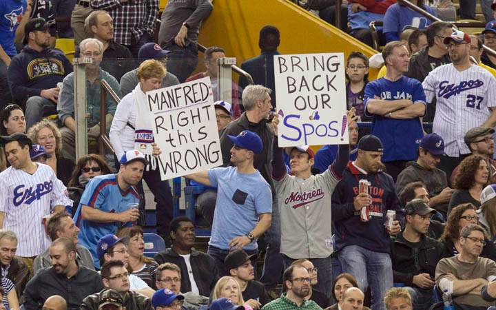 Fans hold up signs as the Toronto Blue Jays face the Cincinnati Reds in Grapefruit League play on April 3, 2015 in Montreal. 