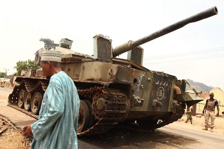 A man walks by a tank left by Boko Haram militants between Michika and Marabara, two cities recaptured from Boko Haram by the Nigeria military early this year, on May 10, 2015.