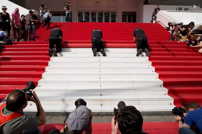 Members of the media surround workers laying down the red carpet on the steps of the Palais des Festivals ahead of the 68th international film festival, Cannes, southern France, Wednesday, May 13, 2015. The festival has elevated security measures for 2016.