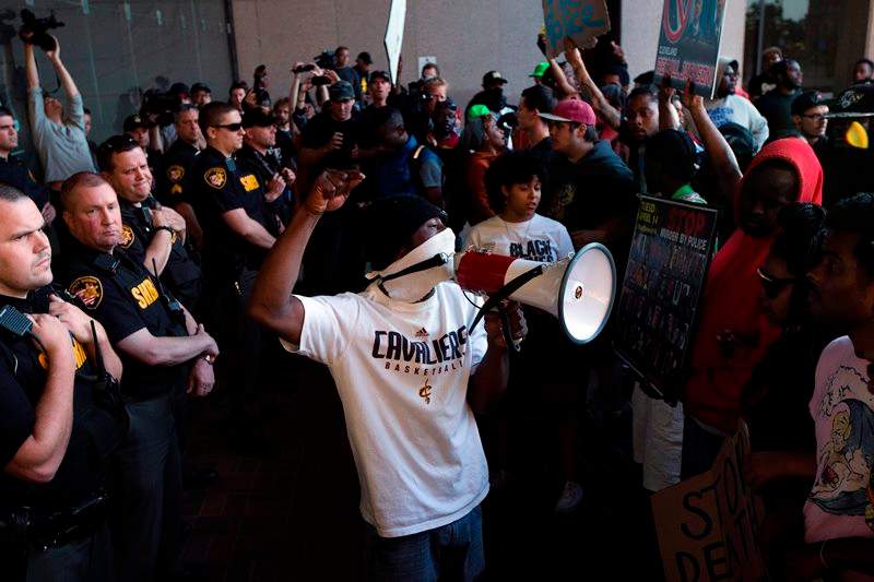 Demonstrators pause at the entrance to the Cuyahoga County Justice Center as police stand guard during a protest against the acquittal of Michael Brelo, a patrolman charged in the shooting deaths of two unarmed suspects, Saturday, May 23, 2015, in Cleveland. 