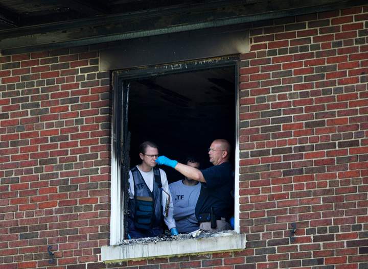 Investigators inspect the fire-damaged multimillion-dollar home in northwest Washington home, Wednesday, May 20, 2015, where four people were found dead May 14.