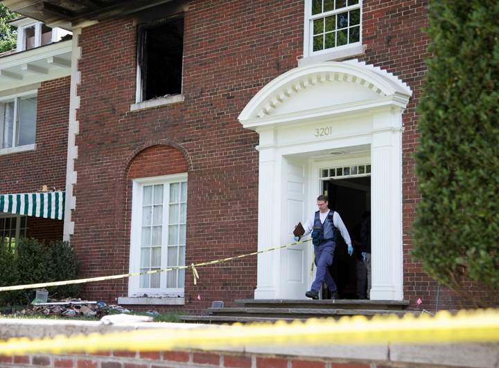 A Bureau of Alcohol, Tobacco, Firearms and Explosives investigator walks out of the fire-damaged multimillion-dollar home in northwest Washington, Wednesday, May 20, 2015, where four people were found dead May 14.