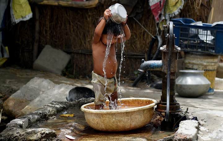 A young Indian child pours water on himself as he tries to cool himself off in New Delhi on May 28, 2015.