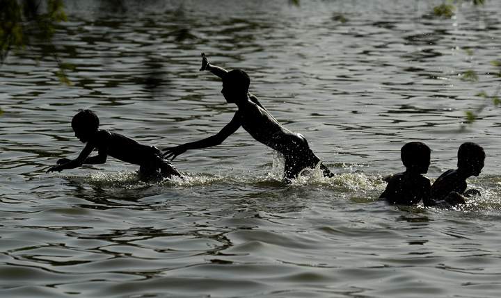 Indian children play in a pond near India Gate amid soaring temperatures in New Delhi on May 27, 2015.