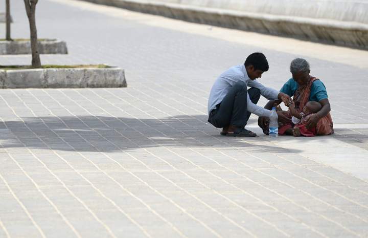 A man plays with his child resting on her grandmother’s lap as they sit in the shade of a tree in Mumbai on May 26, 2015.