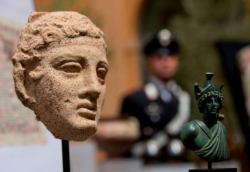 A third century B.C. terracotta head, left, and a second century Roman bronze figure representing Mars, are shown during a press conference in Rome, Tuesday, May 26, 2015.