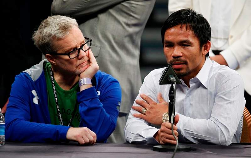 In this May 2, 2015 photo, trainer Freddie Roach listens to Manny Pacquiao  during a press conference.