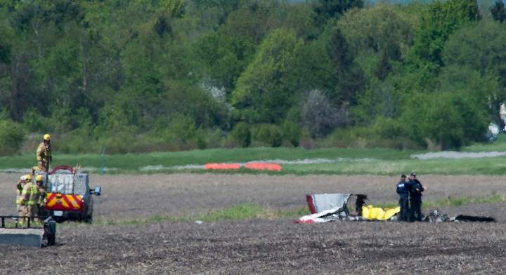 Police and emergency crews survey the scene near St-Lazare airport west of Montreal, Thursday, May 14, 2015, where a small plane crashed in a farmers field.