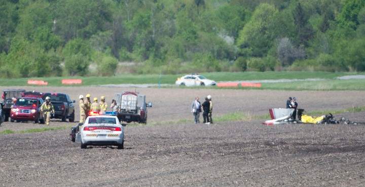 Police and emergency crews survey the scene near St-Lazare airport west of Montreal, Thursday, May 14, 2015, where a small plane crashed in a farmers field.