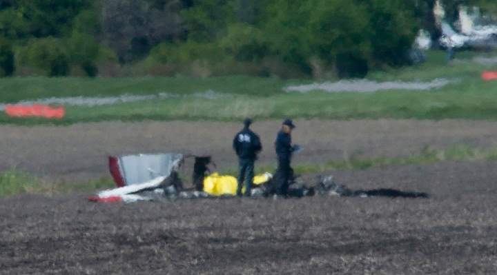 Police and emergency crews survey the scene near St-Lazare airport west of Montreal, Thursday, May 14, 2015, where a small plane crashed in a farmers field.