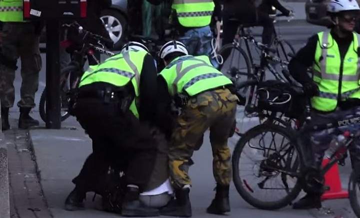 A still from a video that surfaced showing a man seemingly being hit in the face by Montreal police officers during May Day demonstrations.