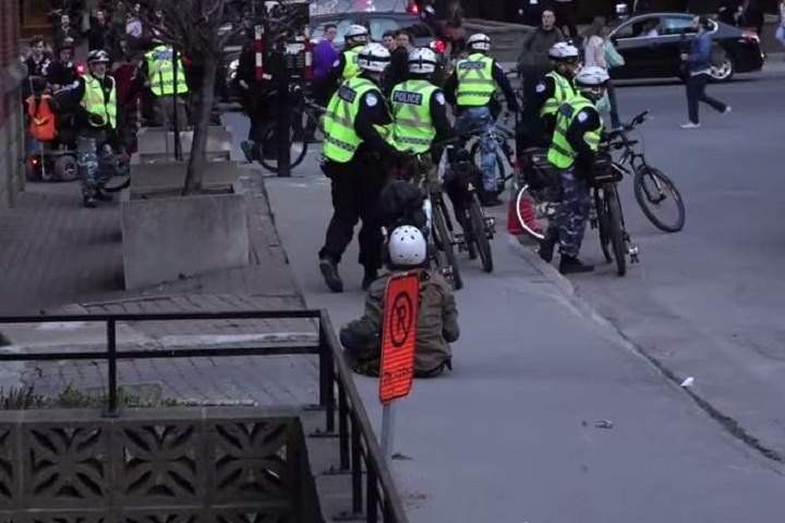 A still from a video that surfaced showing a man seemingly being hit in the face by Montreal police officers during May Day demonstrations.