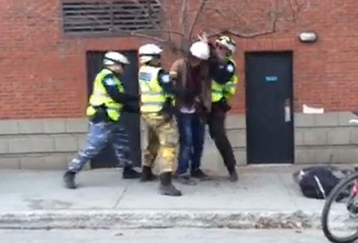 A still from a video that surfaced showing a man seemingly being hit in the face by Montreal police officers during May Day demonstrations.