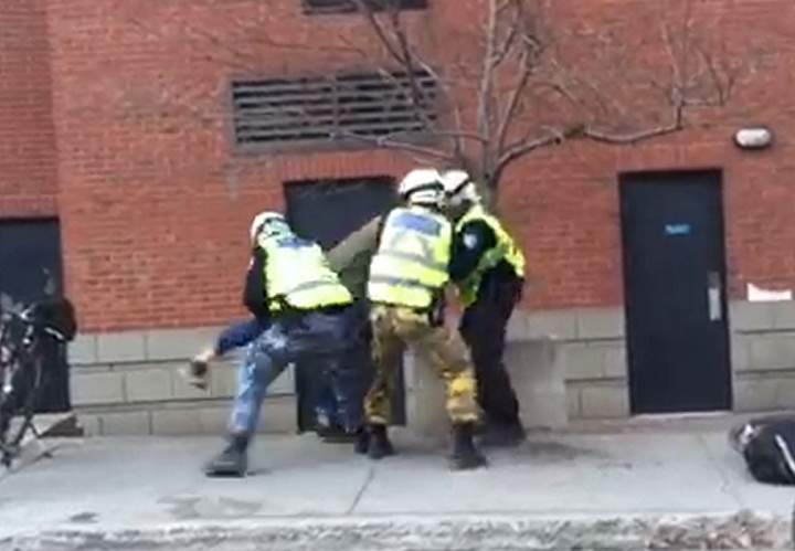 A still from a video that surfaced showing a man seemingly being hit in the face by Montreal police officers during May Day demonstrations.