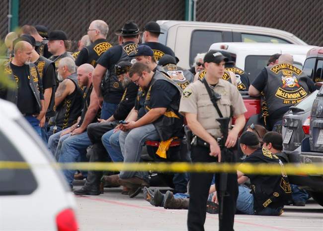 A McLennan County deputy stands guard near a group of bikers in the parking lot of a Twin Peaks restaurant Sunday, May 17, 2015, in Waco, Texas